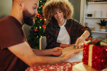 Young couple exchanging christmas presents at home