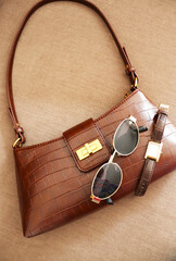 Women accessories. Fashionable brown bag and sunglasses on beige background