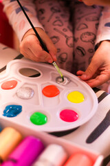A young child is joyfully painting with bright colors on their palette, fully engaged