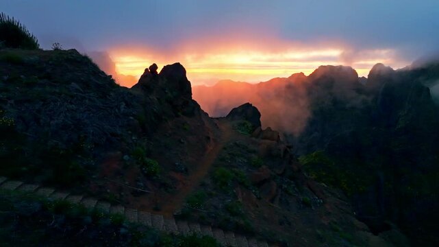 Mountains on sunset covered in fog and clouds with blooming Cytisus shrubs. Near Pico de Arieiro , Madeira island, Portugal. Slide trucking shot