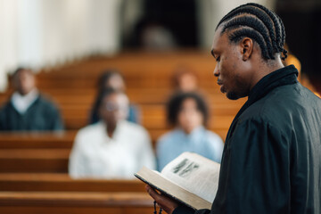 Young priest reading holy book during church service