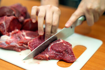 skilled hand expertly slices fresh beef into precise pieces, showcasing art of butchery. glistening meat reflects mastery and tradition culinary craftsmanship