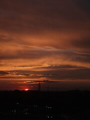 Obraz premium Sunset over the city with car headlights and an orange sky with sun and clouds