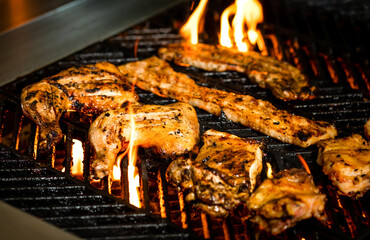 Sizzling Mixed Grill with Chicken, Bacon, pork belly strips, and Flames on the hot grill closeup side view live grilling bbq