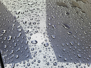 Raindrops and reflections on a dark car in rainy weather