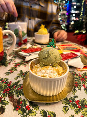 Festive dessert table with holiday-themed decorations. a warm crumble topped with a scoop of ice cream and a Christmas tree decoration captures the cozy atmosphere of a winter celebration. Festive and