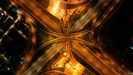 Fototapeta premium Aerial drone long exposure night shot of highway multilevel junction highway with light traffic leaving car headlights white and red trails