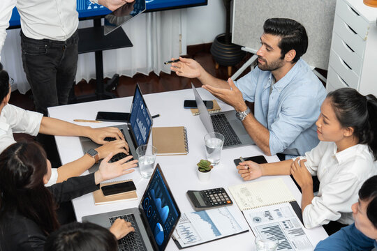 Analyst team utilizing BI Fintech to analyze financial data at table in meeting room. Businesspeople analyzing BI dashboard power for business insight and strategic marketing planning. Prudent
