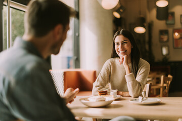 A joyful conversation over coffee and dessert in a cozy café during a sunny afternoon