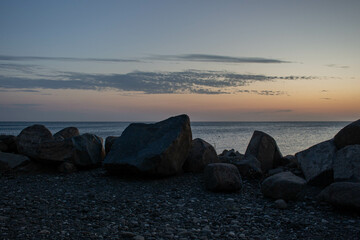Sunset over the sea. Beautiful sky over the sea. Large stones on the beach.
