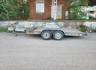 A small open empty cargo trailer is parked in the yard.
