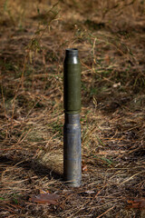 Fired ammunition, two shell casings standing on top of each other, without a combat element in the dry grass. Close-up color vertical photo.