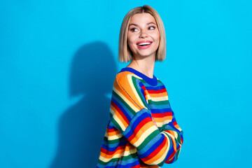 Photo of attractive young woman crossed arms turn around look empty space dressed stylish striped clothes isolated on blue color background