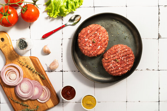Burger patties with fresh ingredients on table
