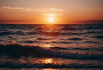 Obraz premium The warm glow of the setting sun casts golden hues over the tranquil waves of the ocean, creating a serene atmosphere by the shoreline during dusk. Sunset or sunrise at sea. Romantic landscape. AI