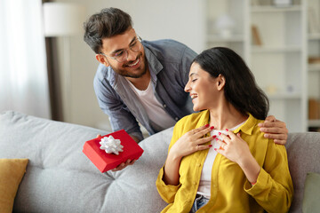 Loving hindu husband giving present gift box to his beloved wife, celebrating birthday, having...