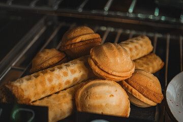 Modern bakery or patisserie. A dessert of nuts with condensed milk with a pie nearby. A display case of a bakery or coffeeshop. Various types of mini desserts in a display case.
