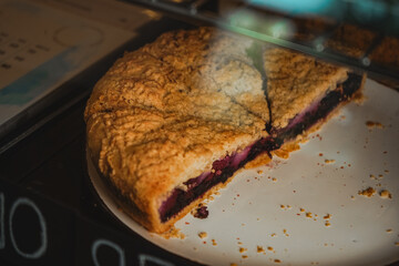 Different kinds of tarts at cafes or coffeeshops. Delicious variety of cakes and pastries at cafe. Half of blueberry pie on black plate in display case at cafes.
