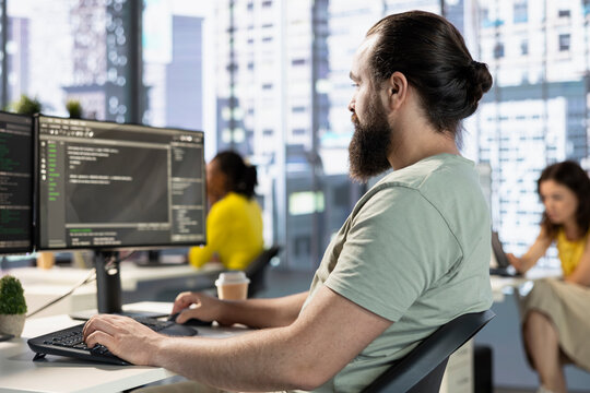 Computer scientist testing and debugging company software to minimize occurrence of bugs, identifying bottlenecks. IT expert in office writing clean code in programming language to reduce errors