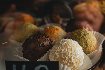 Dessert in the form of round balls of different colors in display case. A view of a display of assorted European pastries,inside a bakery shop. Delicious variety of cakes and pastries at cafe.
