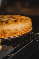 A photo of part of chicken pie front view close up. Display case with a variety of cakes and...