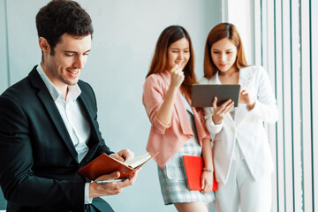 Happy young handsome businessman reading book and working in office with colleagues and friend at workplace. Corporate business people group. uds