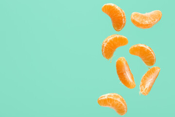 Flying pieces of sweet peeled mandarin on turquoise background