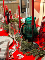 Christmas set table is adorned with festive decorations, ready for a joyful winter holiday gathering. Vibrant red tablecloth and elegant tableware create a warm and inviting atmosphere