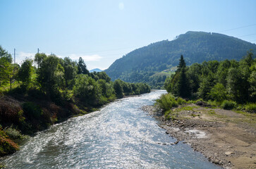 The clear water of Black Cheremosh river flowing through a picturesque valley surrounded by dense...