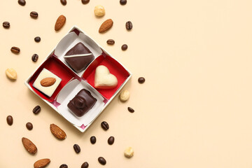 Delicious chocolate candies in box, nuts and coffee beans on beige background