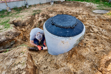 Plumber connects drainage pipe to septic tank outlet pipe to carry wastewater into drain field.