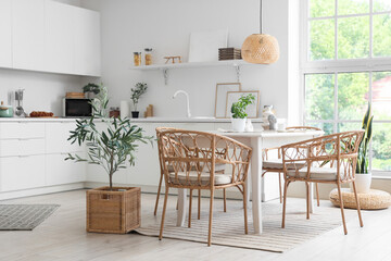Interior of light dining room with table and wicker chairs