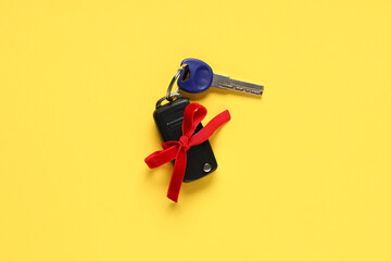 Gift keys of new car with bow on yellow background