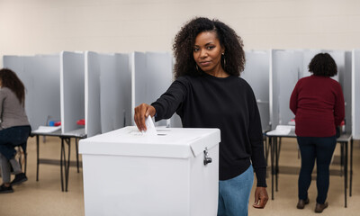 african american woman casting her vote, putting ballot in ballot box