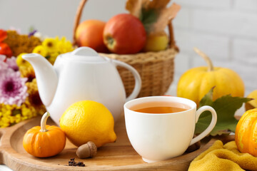 Tea pot, cup of tasty green tea, wooden tray, pumpkins, plaid and wooden tray on table in room, closeup