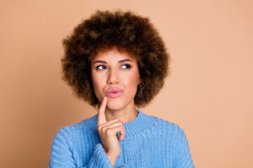 Photo of young lady with brown hair chevelure in blue knitted sweater touch chin finger looking new brand release isolated on beige color background