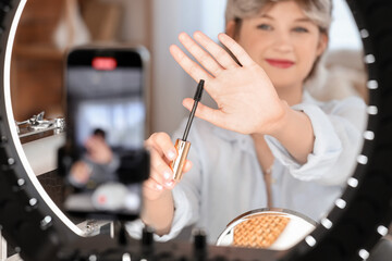 Female beauty blogger with mascara recording video at home, closeup