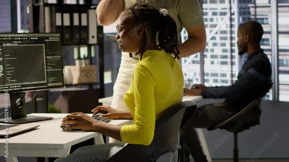 Poster manager coming to check on it employee at office desk testing and deploying programs and systems. te