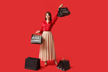 Young woman with shopping bags on red background. Black Friday Sale
