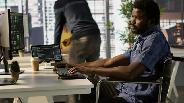 Software technician with disability in inclusive workplace working with machine learning tech. African american IT expert with paraplegia in wheelchair transforms data into predictive models