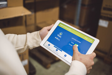 The young female owner and the man in the warehouse check the temperature, energy consumption and lights on a tablet.