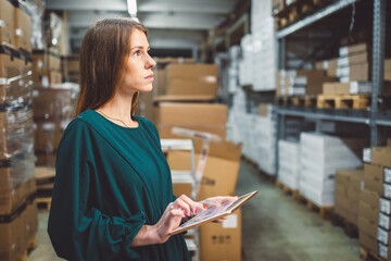 Fototapeta premium The young female owner and the man in the warehouse check the temperature, energy consumption and lights on a tablet.
