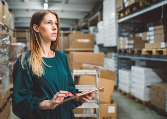 The young female owner and the man in the warehouse check the temperature, energy consumption and lights on a tablet.