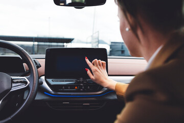 A woman in an electric car uses a screen to control the car's settings