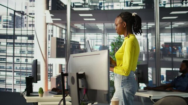 Computer scientist working, doing software debugging using notebook, troubleshooting errors. Woman standing in office, fixing coding issues using laptop, solving tasks, camera B