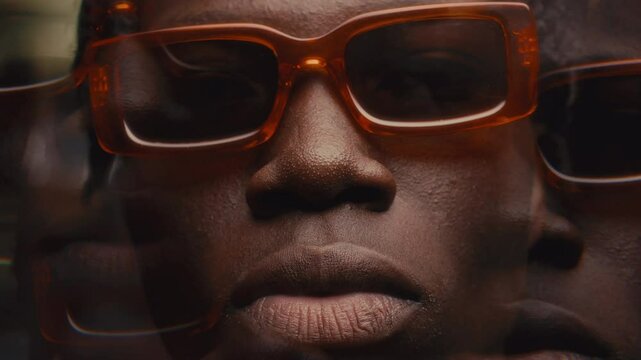 Kaleidoscopic effect of cool-looking Black man wearing trendy orange sunglasses looking confidently at camera with serious expression. Video portrait
