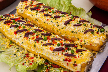 Causa Limeña is a traditional Peruvian dish that features layers of mashed potatoes seasoned with lime, aji amarillo (Peruvian yellow chili pepper),