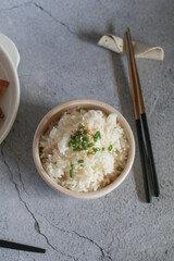 Steamed rice with black sesame seeds and spring onion in ceramic bowl on table. Thailand and Asia eat with food.