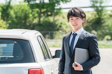 車の査定をするカーディーラの査定士・営業マンの若いアジア人男性
