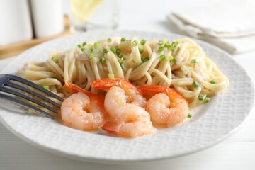 Delicious pasta with shrimps and green onions on white table, closeup